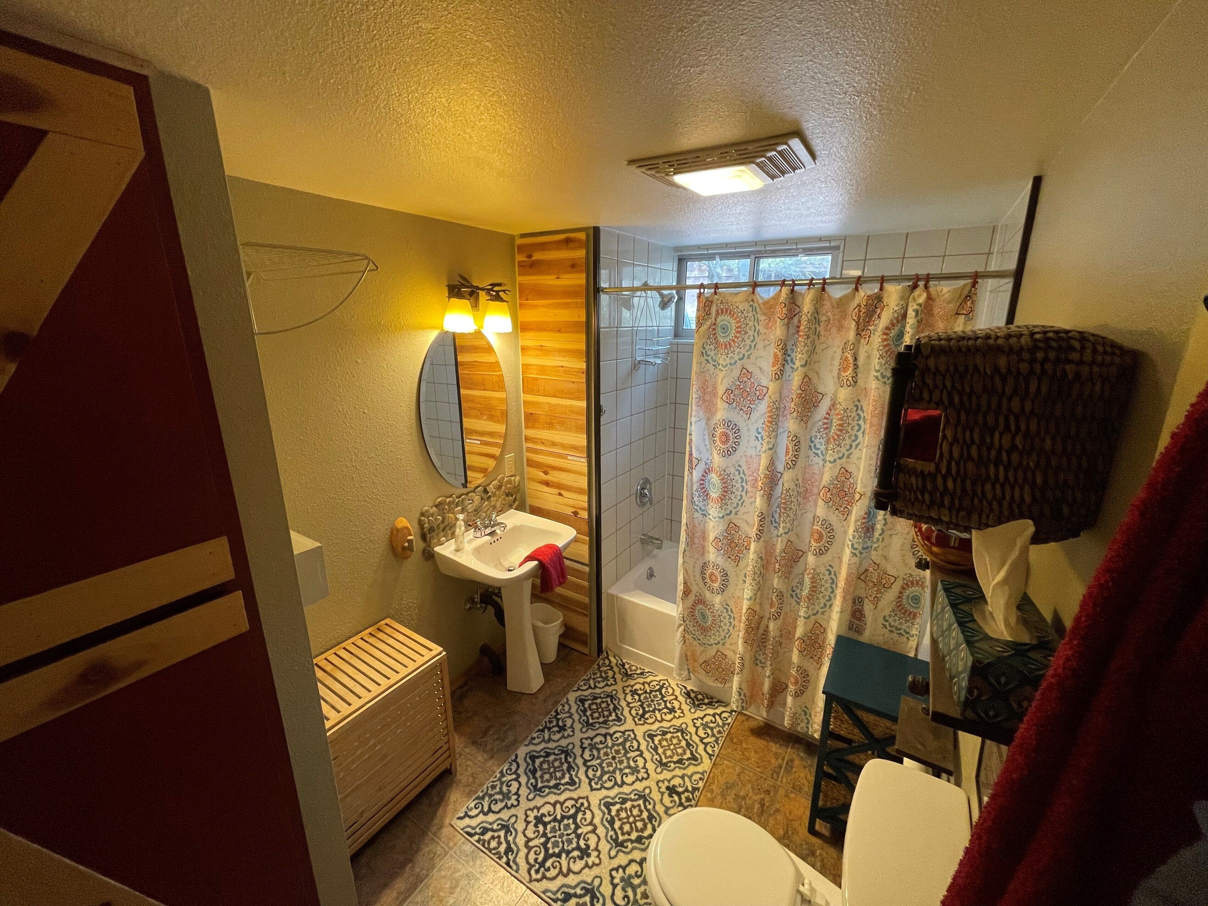 A bathroom with a wooden vanity, a sink, a toilet, and a shower area.