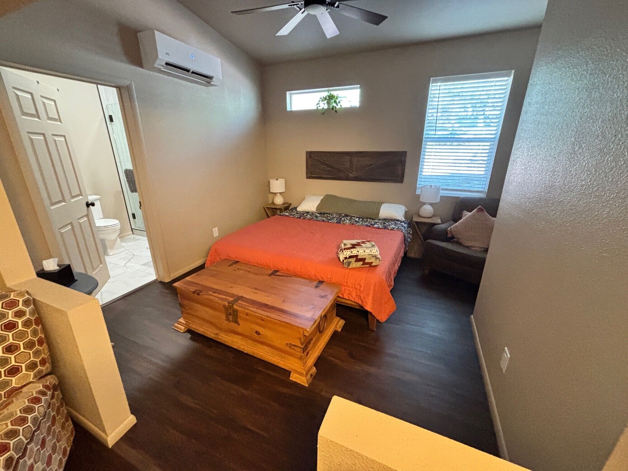 Un dormitorio con cama, cómoda, ventana y aire acondicionado.