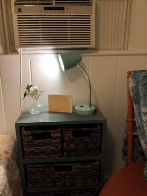 Ett hörn med en lampa, en vas med blommor, ett kort och korgar av rotting på en hylla.
