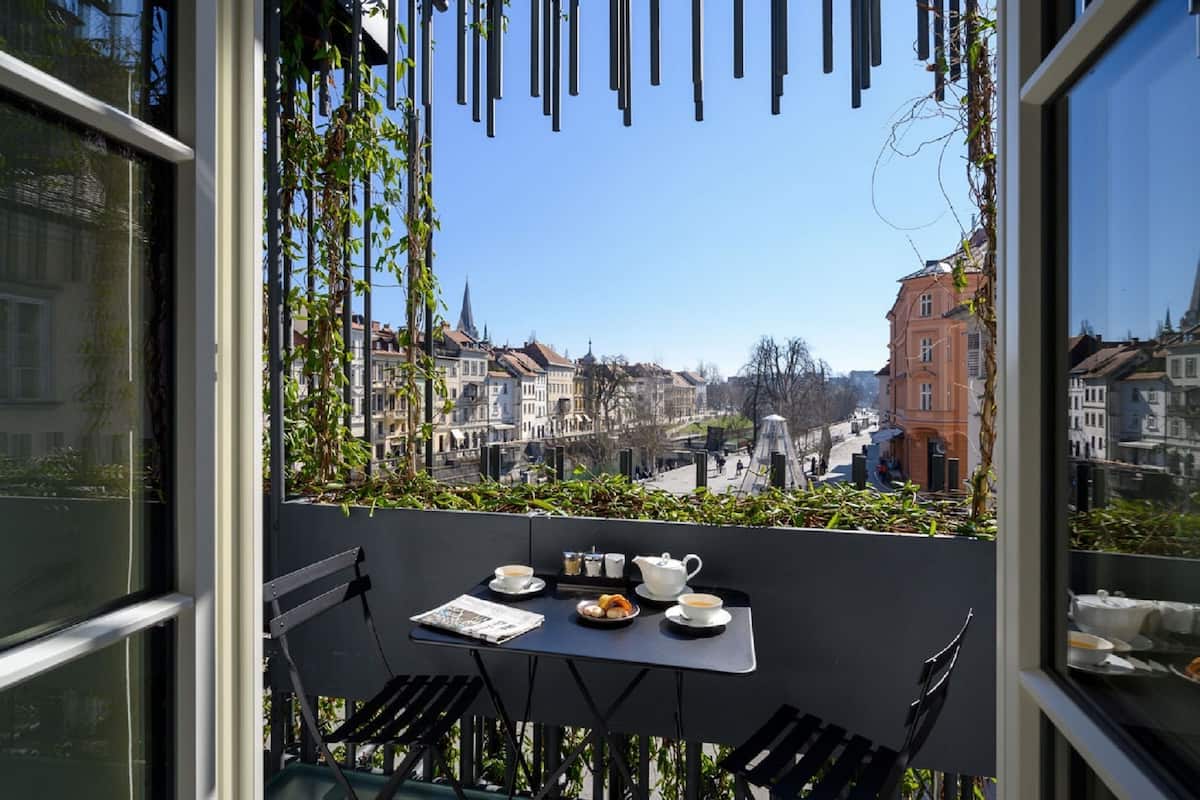 Ein Balkon mit Tisch für zwei Personen, mit Blick auf eine Stadtlandschaft und historische Gebäude.