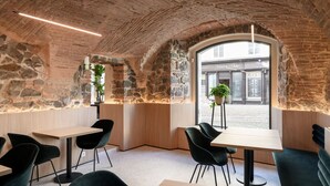 Um interior moderno com paredes de pedra, mesas de madeira e cadeiras pretas.