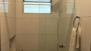 A walk-in shower with a glass door, a towel rack, and a small window.