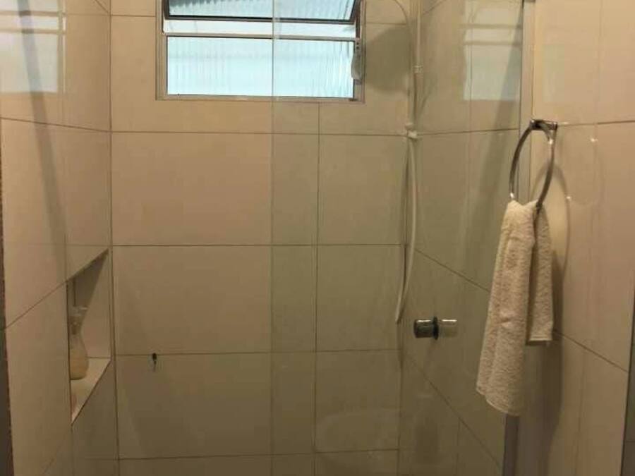 A walk-in shower with a glass door, a towel rack, and a small window.
