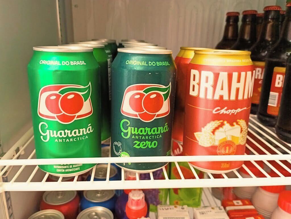 A refrigerator shelf with cans of Guarana Antarctica Zero and Brahma beer.