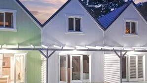 Una fila de tres casas con porches incorporados, cada una con un ventanal corredizo que da a un espacio al aire libre.