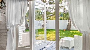 Una habitación con puerta de vidrio corredera que da a un patio exterior con mobiliario de mimbre y césped.