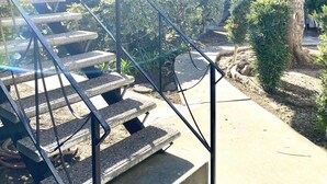 Eine Treppe führt zu einem Gebäude, im Vordergrund steht ein Baum.