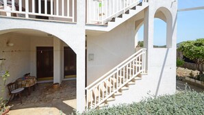 A two-story building with a balcony, a staircase, and a patio area with outdoor furniture. - Gorgeous apartment in Racisce with house sea view (Racisce)