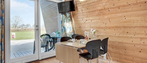 A dining area with a table, chairs, a TV, and a view of the outdoors.