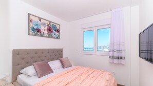 Une chambre à coucher avec un lit, une fenêtre donnant sur un beau paysage, un tableau accroché au mur et un rideau.