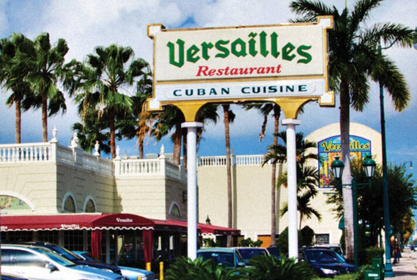 A sign for 'Versailles Restaurant' with a 'Cuban Cuisine' label, surrounded by palm trees and a parking area.