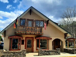 A traditional chalet-style building with a balcony, stone foundation, and a sign indicating it is part of the Christoffel Village in Munich. - Welcome to the Heart of Helen, Chalet Munich (Helen)