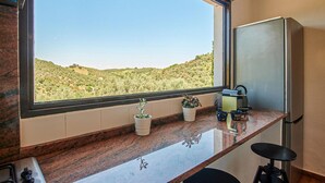 A kitchen with a large window, a refrigerator, a coffee maker, and a potted plant. - Nice home in Constantina (Constantina)