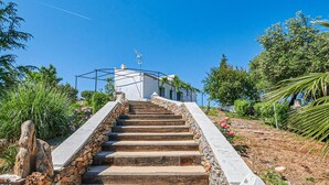 A staircase leading to a white building with a metal structure on top, surrounded by greenery and trees. - Nice home in Constantina (Constantina)