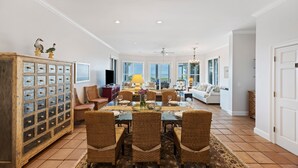 A spacious living room with a dining area, large windows, and a ceiling fan. - Ocean View Home in Gated Wild Dunes on Golf Course & Pool Access! (Isle of Palms)