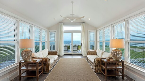 A room with a large window, a ceiling fan, and two side tables with lamps. - Ocean View Home in Gated Wild Dunes on Golf Course & Pool Access! (Isle of Palms)