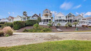 A beachfront property with multiple houses, each featuring balconies and a sandy beach in the foreground. - Ocean View Home in Gated Wild Dunes on Golf Course & Pool Access! (Isle of Palms)