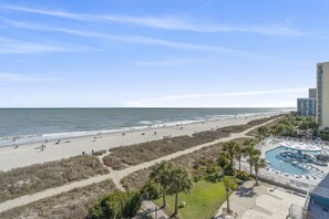A beach resort with a pool area, a boardwalk, and a view of the ocean.