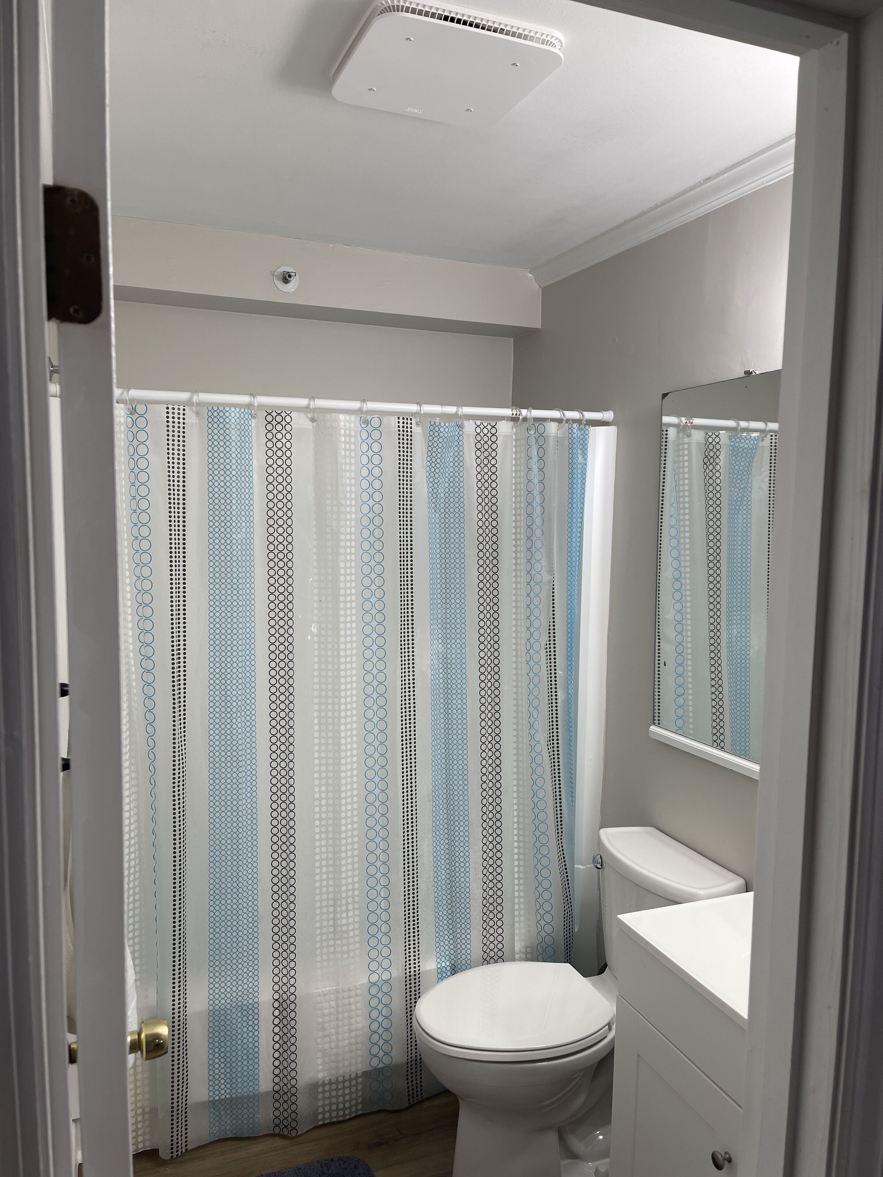 Un baño con inodoro, lavamanos y cortina de ducha con diseño geométrico.