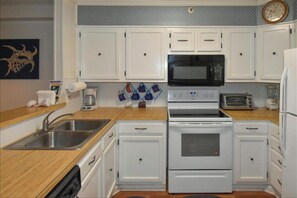 Compact kitchen area with a stainless steel sink, microwave, toaster, and oven.