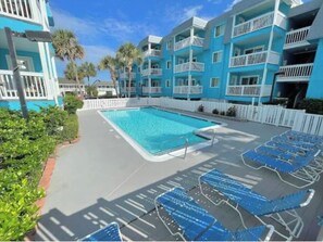 Relax by the pool surrounded by a white fence, with lounge chairs and a rectangular pool.