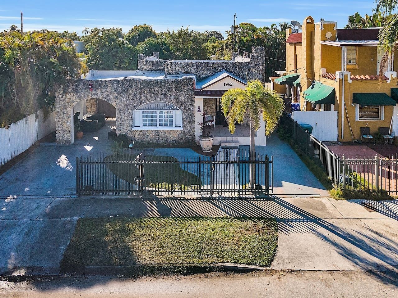 Zona residencial con muro de piedra, entrada con reja y una casa con el número 1742 en la fachada.