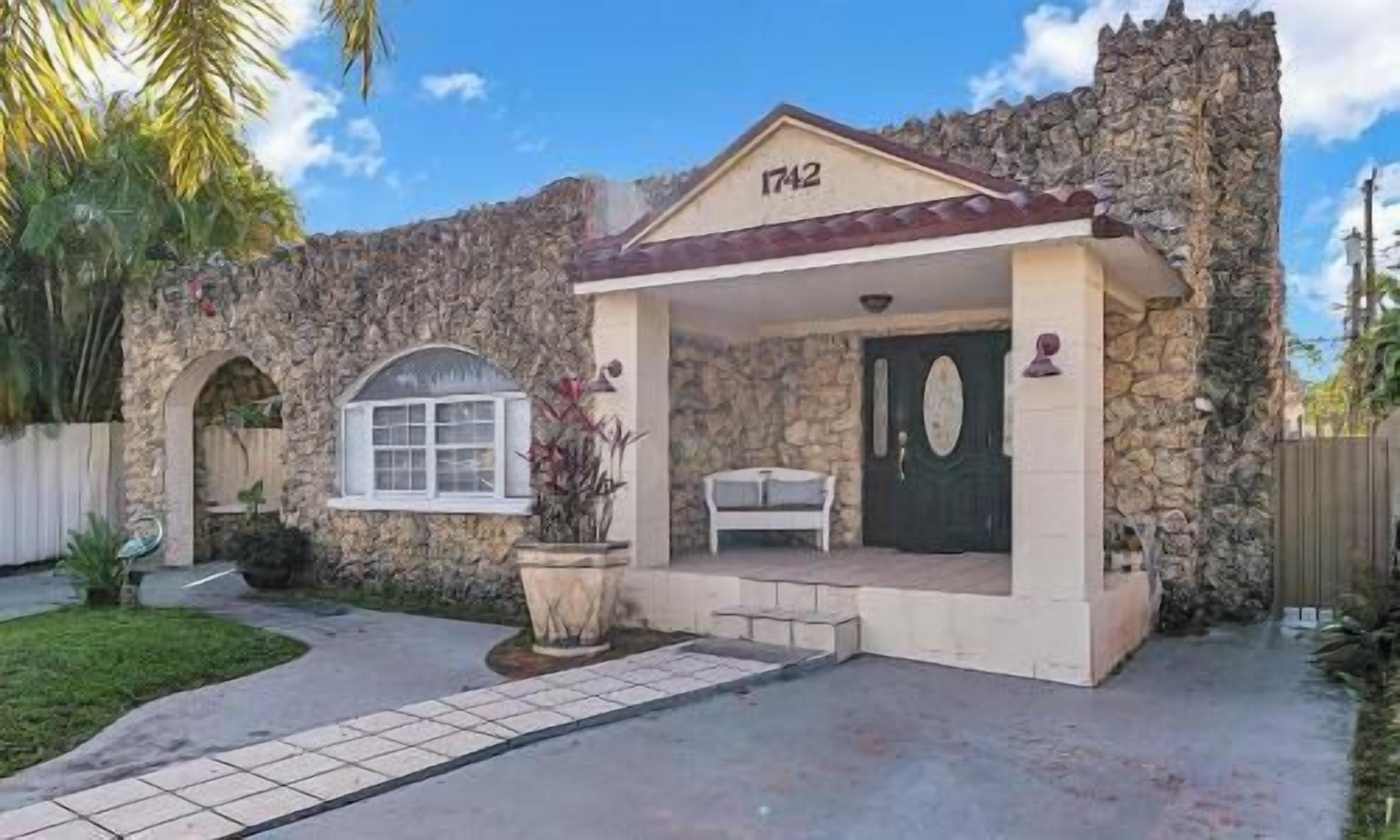 Un bâtiment en pierre dont la façade porte le numéro « 1742 », avec un porche et un petit jardin.
