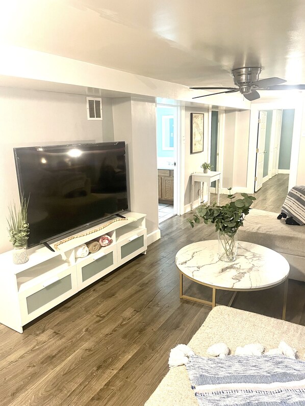 Relax in this stylish living room with a flat-screen TV, comfortable sofa, and cozy throw blanket.
