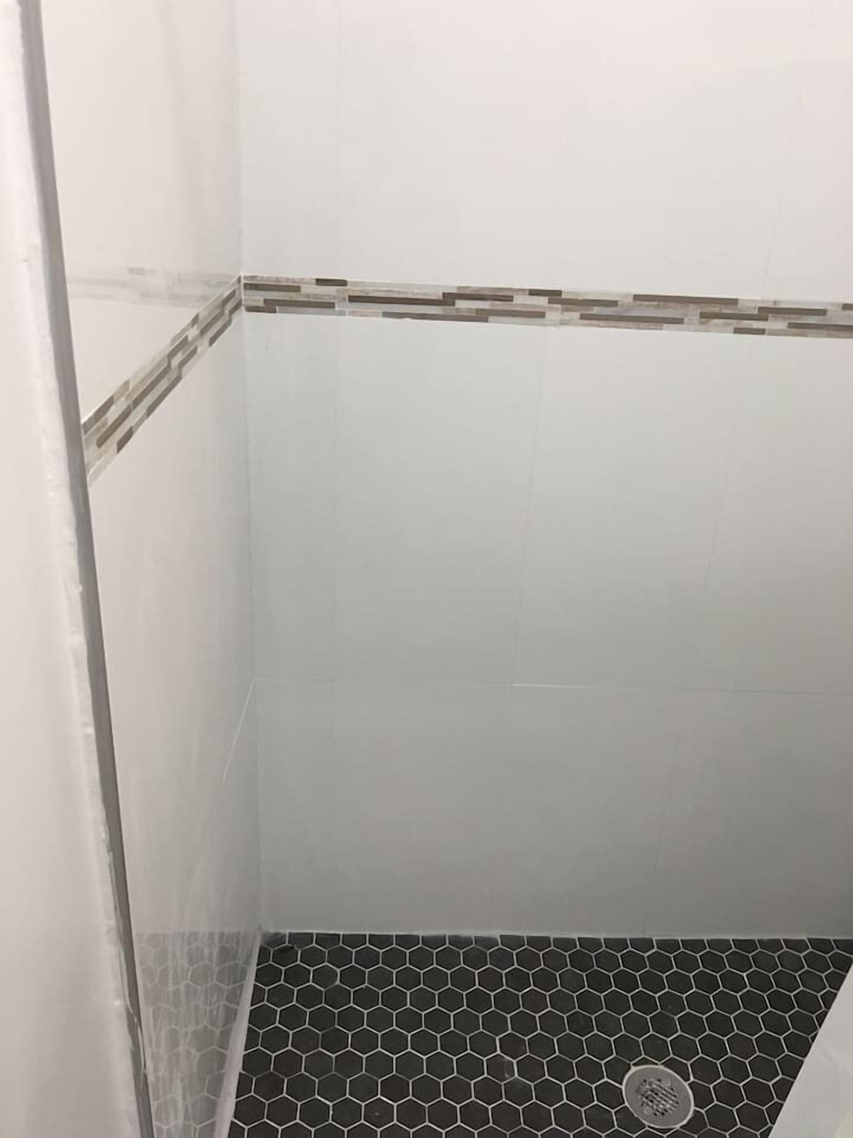 A corner of a room with white tiled walls and a hexagonal patterned floor.