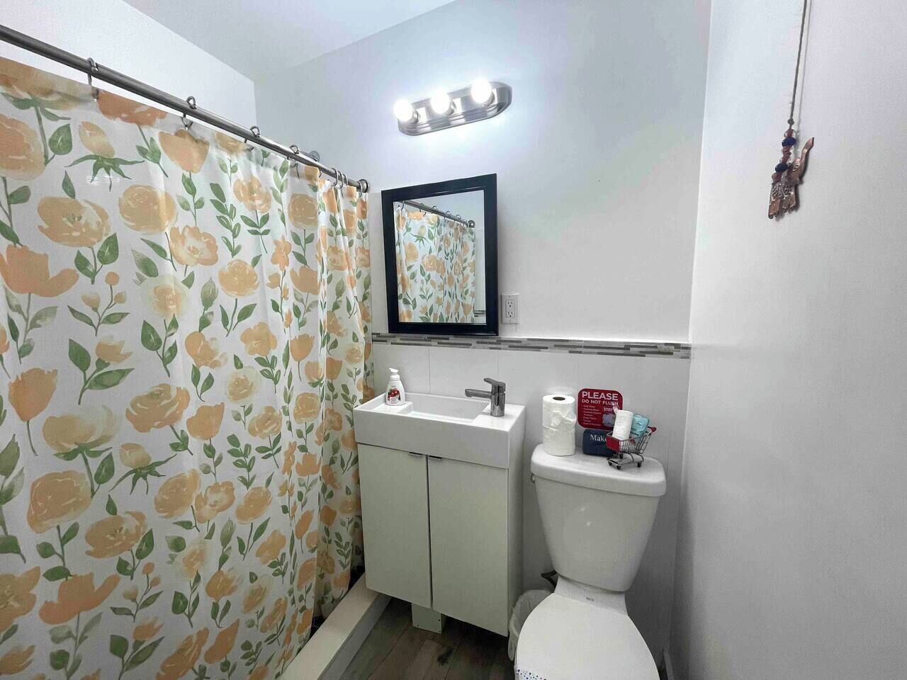 A bathroom with a shower curtain, sink, mirror, and toilet.