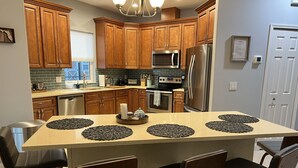 Une cuisine moderne avec des meubles en bois, des appareils électroménagers en acier inoxydable et un îlot central doté de chaises.