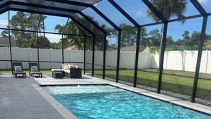 Une piscine dotée d’un espace couvert, d’un revêtement de sol en carrelage et de mobilier d’extérieur.