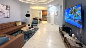 Un salon moderne avec un canapé marron, une table basse et un téléviseur posé sur un meuble.