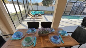 Un espace de restauration en plein air avec une table en bois prévue pour quatre personnes, entourée de chaises en osier.