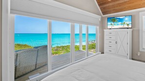 A bedroom with a large sliding glass door leading to a balcony with a view of the ocean. - Shades of Blue a luxury home on private beachfront sleeps 20ppl, chef, boat tour (Forbes Hill)