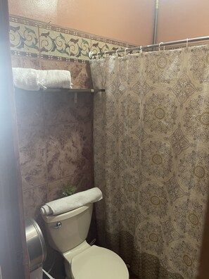 A bathroom with a toilet, a shower curtain with a floral pattern, and a towel hanging on a rack. - Luxurious Central Apt / 5 min from the Airport (Alajuela)