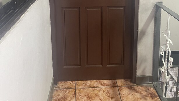 Une porte marron avec une pancarte indiquant « BIENVENUE, amis » au-dessus.
