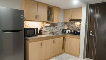 A modern kitchen with wooden cabinets, a stainless steel refrigerator, a microwave, and a sink.