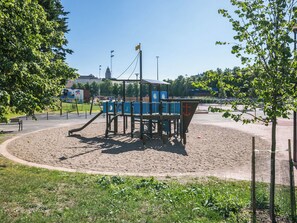 A playground with a climbing structure, surrounded by a fenced area with trees. - Helsinki rooftop by Interhome (Helsinki)