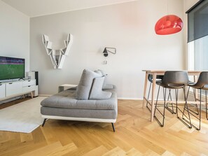 A modern living room with a grey sofa, a TV, a wall-mounted light, and a red pendant light. - Helsinki rooftop by Interhome (Helsinki)