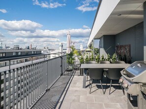 A rooftop terrace with a grill, outdoor seating, and a view of the city skyline. - Helsinki rooftop by Interhome (Helsinki)
