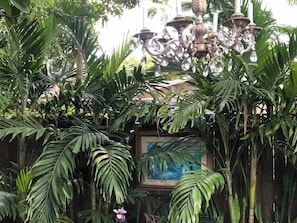 A lush garden with a chandelier, framed artwork, and dense foliage.