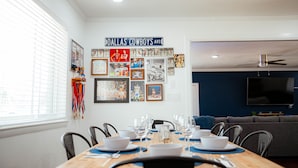 Zona pranzo con tavolo apparecchiato per sei persone, parete decorata con cimeli sportivi e una parete azzurra a contrasto.
