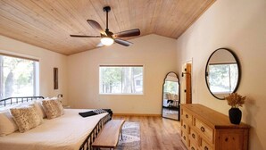 A bedroom with a bed, a dresser, a mirror, and a ceiling fan. - Family Retreat! Hot Tub, King Beds & EV Charger (Arnold)