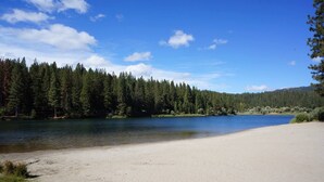A sandy beach with a calm lake, surrounded by dense forest and clear blue sky. - Family Retreat! Hot Tub, King Beds & EV Charger (Arnold)