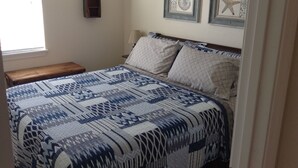 Un dormitorio con cama, mesita de noche, ventana y decoración en las paredes.