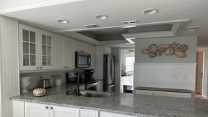 A modern kitchen with white cabinetry, a granite countertop, stainless steel appliances, and a recessed ceiling light.
