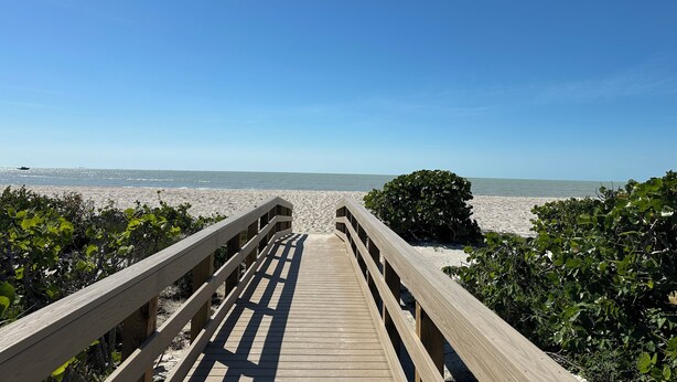 A wooden boardwalk leading to a beach with clear skies.