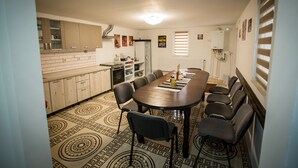Un espace repas avec une longue table, des chaises et une cuisine en arrière-plan.