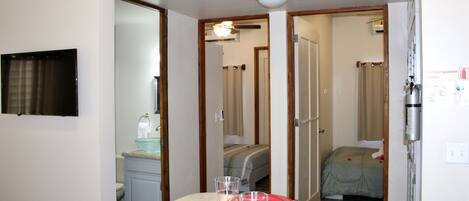 A hotel room with a dining area, a bed, and a bathroom.